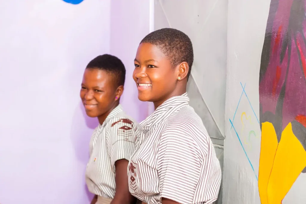 Two school girls smiling inside a school building