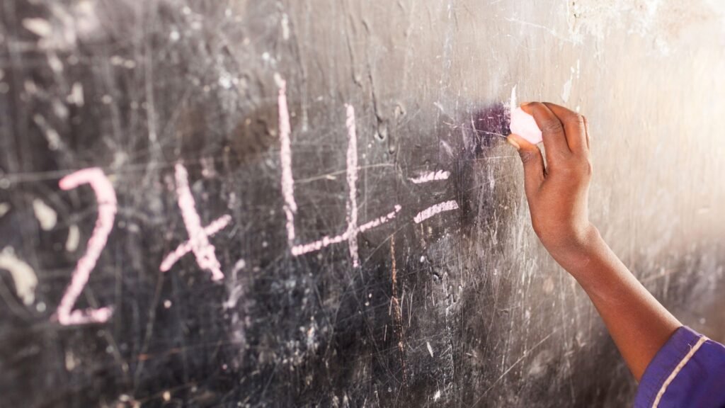 A teacher in a rural Ghana classroom engaging students during a lesson, demonstrating the importance of holistic education.