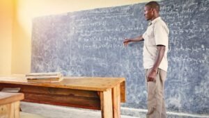 A teacher in a rural Ghana classroom engaging students during a lesson, demonstrating the importance of holistic education.