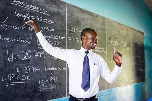 Teacher teaching maths at the blackboard in Ghana, reflecting teacher shortage in Ghana and increased classroom workload