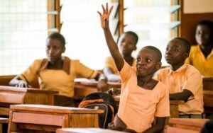 Girl seated in class learning and raising her hand to answer a question