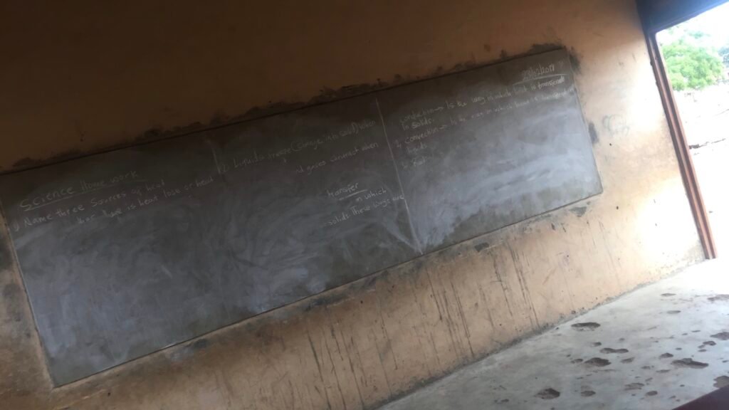 A classroom with a damaged blackboard and deteriorating learning conditions before Homeland Ghana’s renovation interventions.