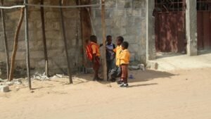 Three students standing together outside a school in Ghana after the school day has ended.