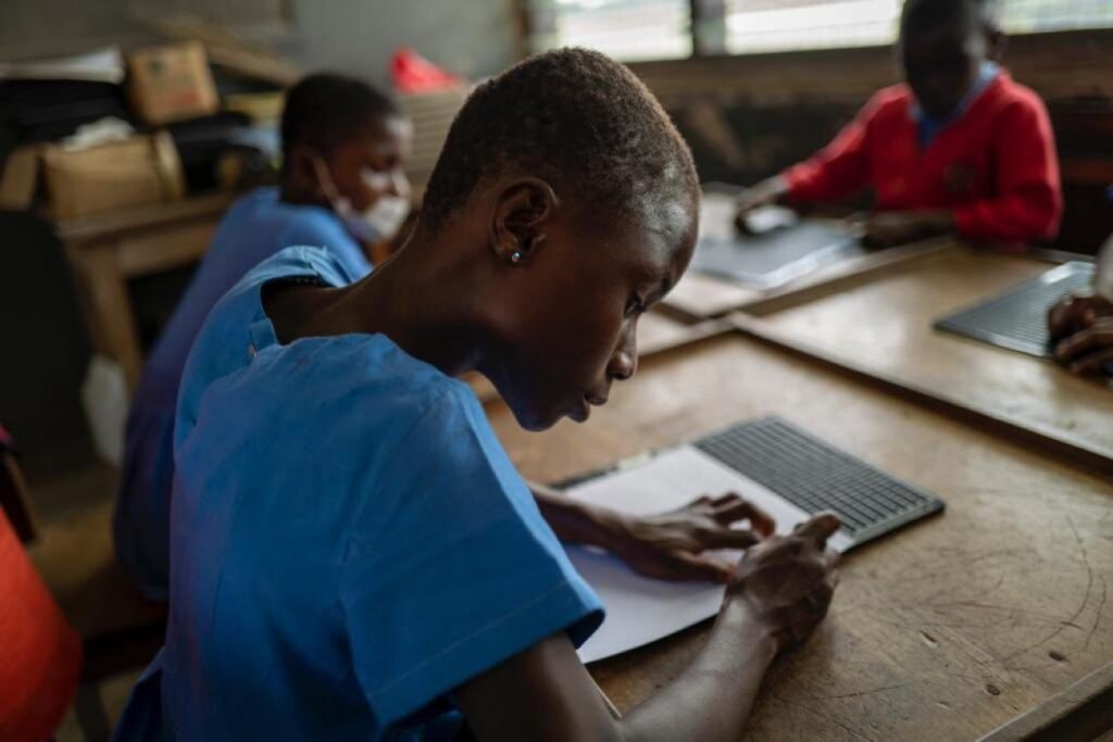 A student reads Braille learning materials during a lesson in a specialist classroom.
