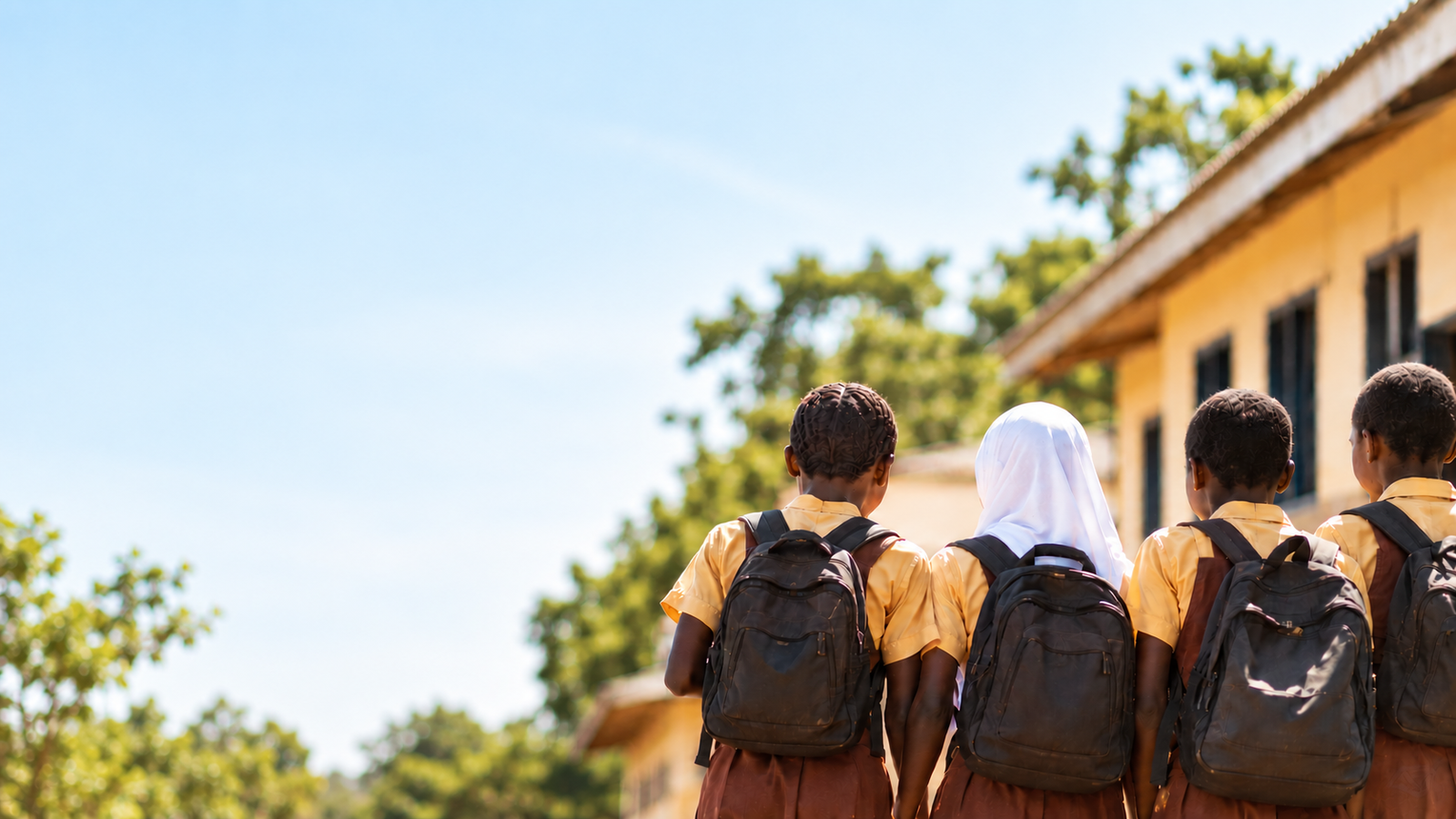 Four Ghanaian students standing together outside a school