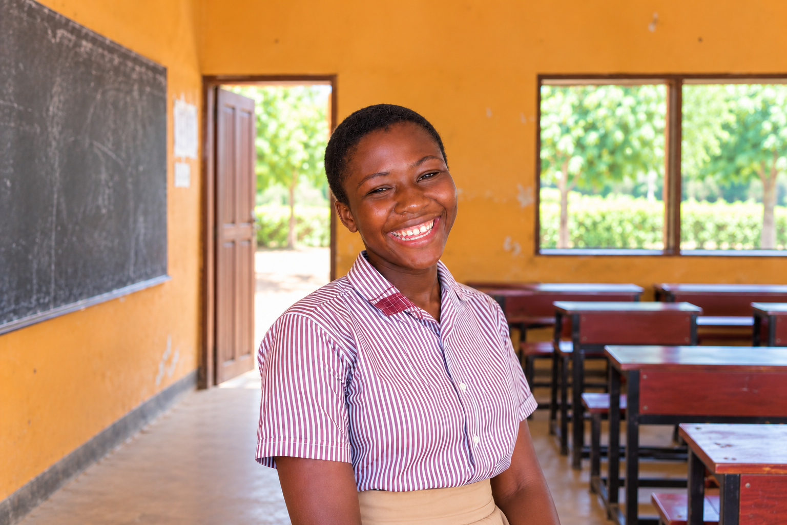 Dora smiling in her school classroom in Ghana.