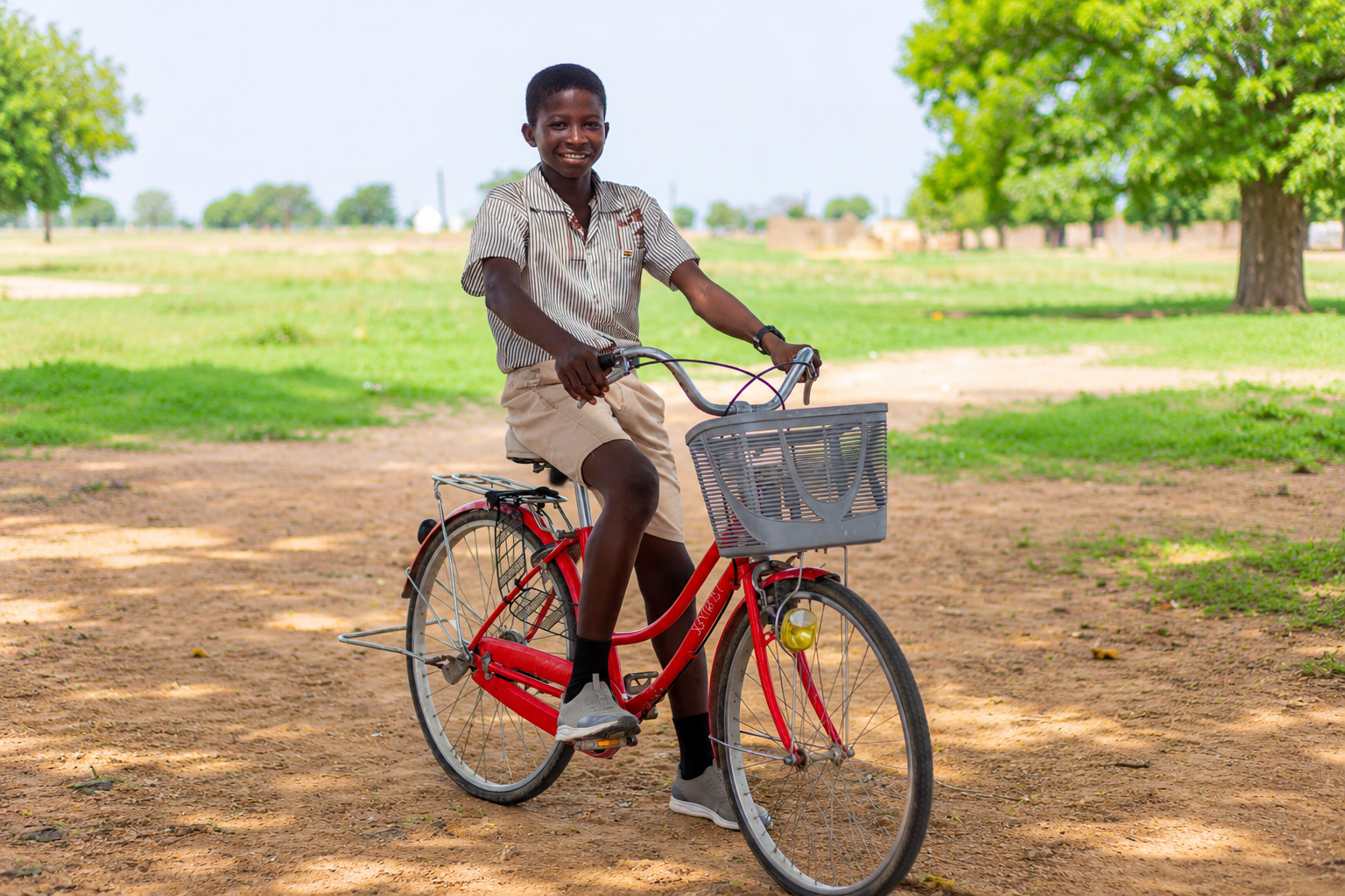 Elisha smiling while sitting on his red bicycle outdoors.